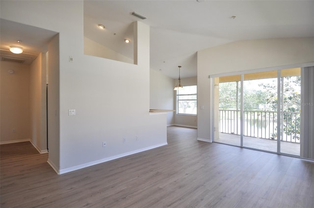 spare room with wood-type flooring, vaulted ceiling, and a notable chandelier