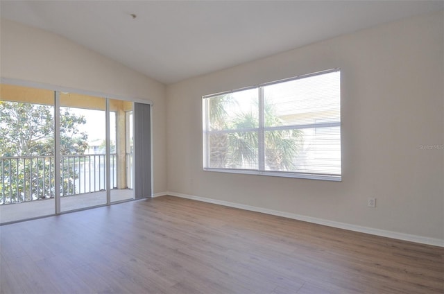 spare room with light hardwood / wood-style floors and lofted ceiling