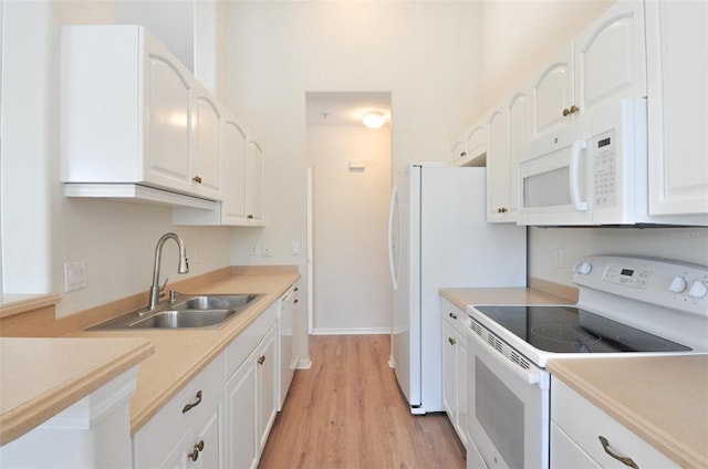 kitchen with white appliances, light hardwood / wood-style floors, white cabinetry, and sink