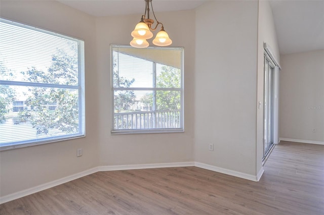 spare room featuring hardwood / wood-style flooring, a healthy amount of sunlight, and an inviting chandelier