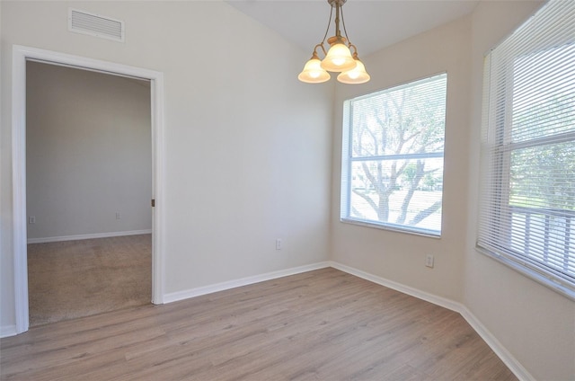 unfurnished room with light hardwood / wood-style flooring and a chandelier