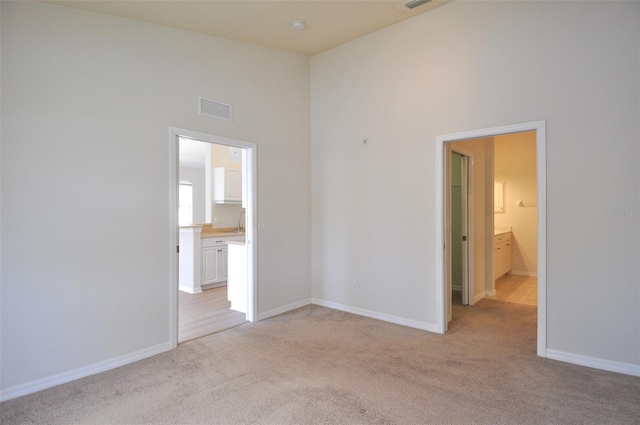 carpeted spare room with a towering ceiling