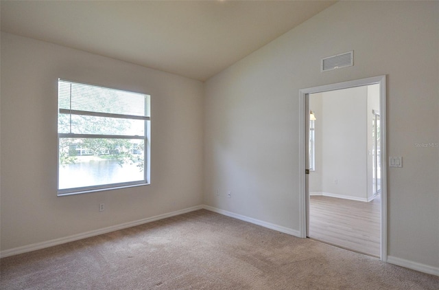 unfurnished room featuring light carpet and lofted ceiling