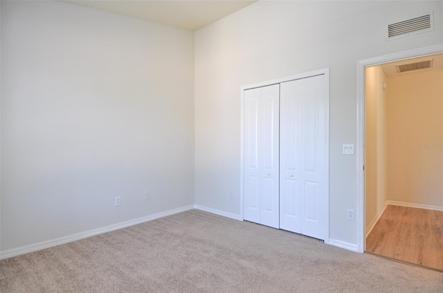 unfurnished bedroom with a closet and light carpet