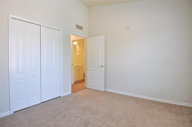 unfurnished bedroom with a towering ceiling, light colored carpet, and a closet