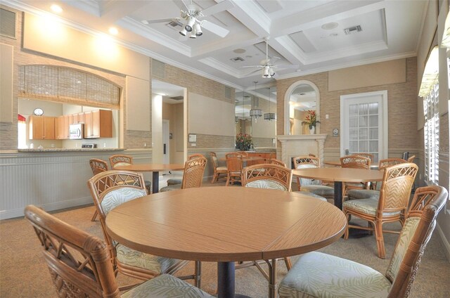 carpeted dining room with ornamental molding, a fireplace, beam ceiling, coffered ceiling, and ceiling fan