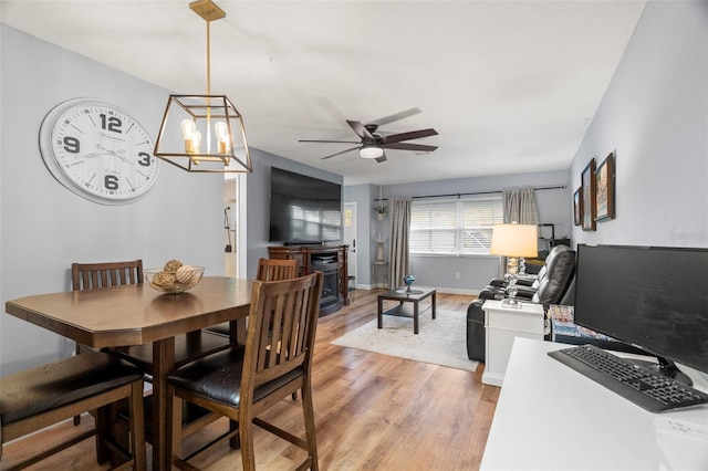 dining space featuring light hardwood / wood-style floors and ceiling fan with notable chandelier