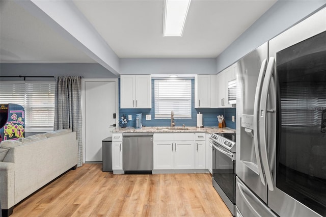 kitchen featuring tasteful backsplash, appliances with stainless steel finishes, sink, light hardwood / wood-style floors, and white cabinets