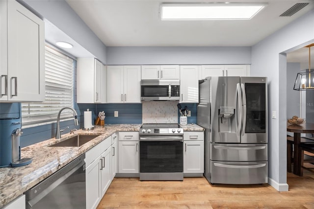 kitchen featuring sink, appliances with stainless steel finishes, tasteful backsplash, white cabinets, and light wood-type flooring