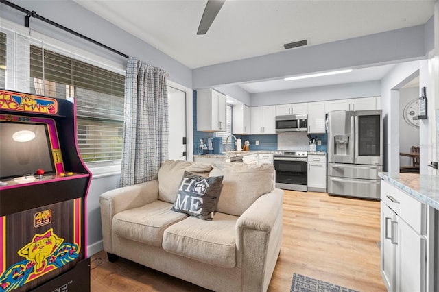 kitchen with light wood-type flooring, white cabinets, and stainless steel appliances