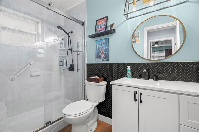 bathroom featuring tile walls, vanity, hardwood / wood-style flooring, toilet, and a shower with shower door