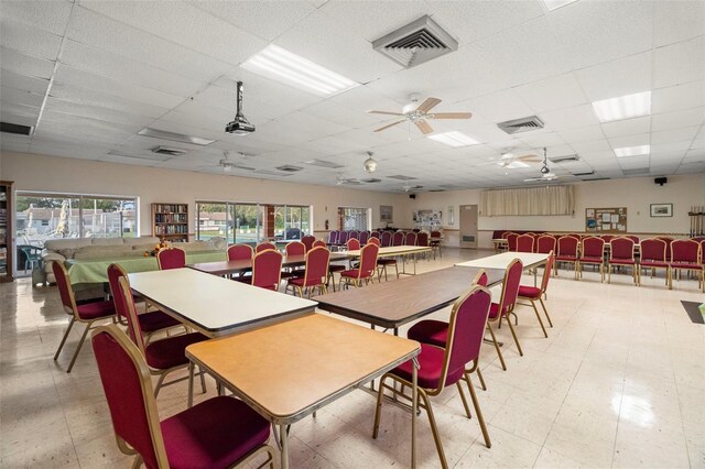 dining space with ceiling fan and a drop ceiling