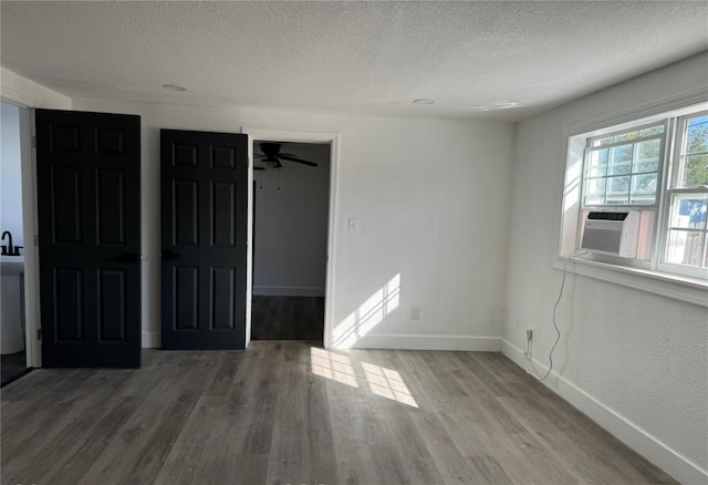 spare room with cooling unit, wood-type flooring, a textured ceiling, and ceiling fan