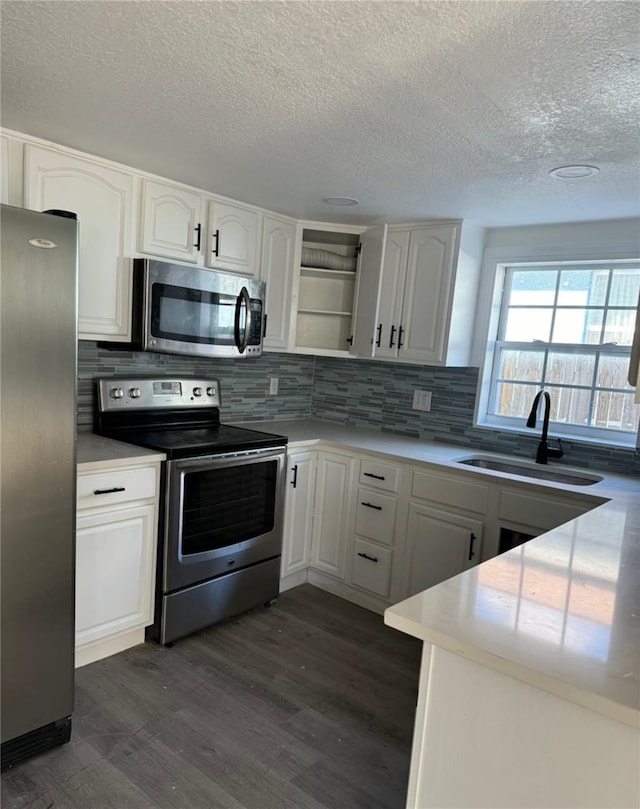 kitchen featuring white cabinetry, appliances with stainless steel finishes, backsplash, sink, and dark wood-type flooring