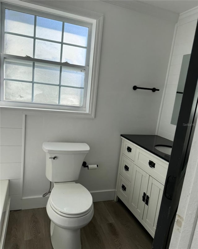 bathroom with a bathing tub, vanity, hardwood / wood-style flooring, and toilet