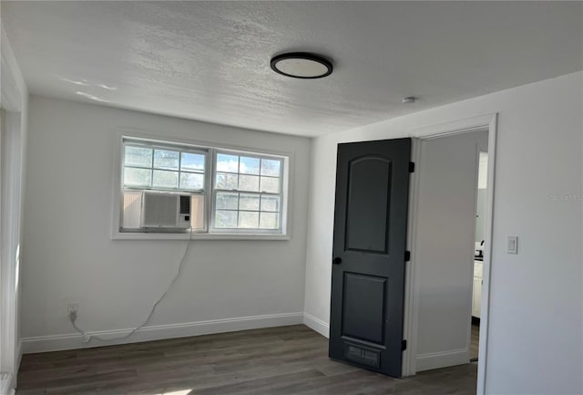 spare room with dark wood-type flooring, a textured ceiling, and cooling unit