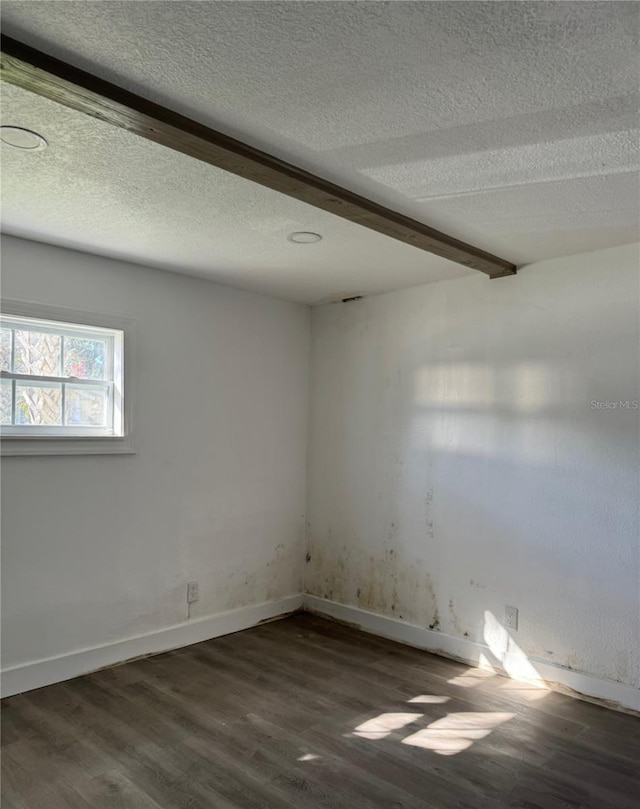 spare room with beamed ceiling, a textured ceiling, and dark hardwood / wood-style floors