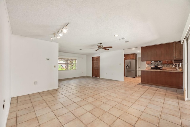 unfurnished living room with ceiling fan, a textured ceiling, and light tile patterned floors