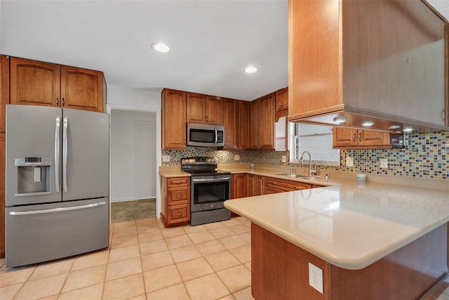 kitchen with appliances with stainless steel finishes, kitchen peninsula, sink, and backsplash