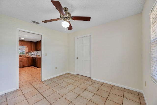 unfurnished room featuring light tile patterned floors, a textured ceiling, and ceiling fan