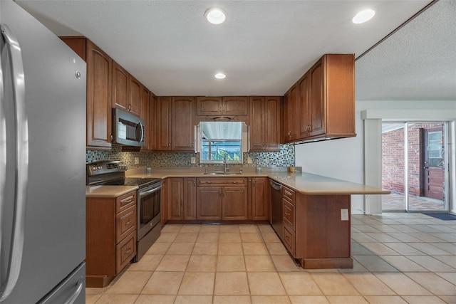 kitchen featuring sink, light tile patterned floors, appliances with stainless steel finishes, kitchen peninsula, and decorative backsplash