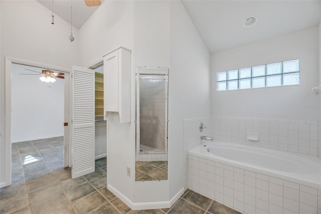 bathroom featuring ceiling fan, lofted ceiling, and tiled tub