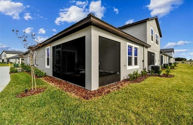 view of side of property with a lawn, central AC, and a sunroom