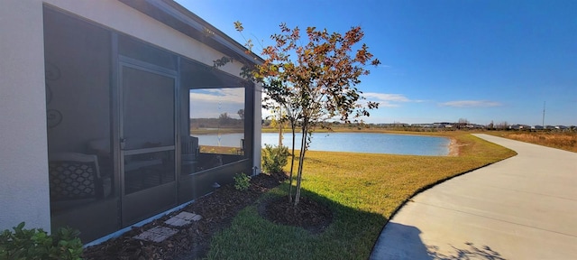 view of yard with a sunroom and a water view