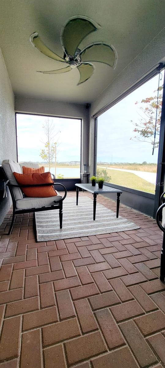 balcony with a water view and ceiling fan