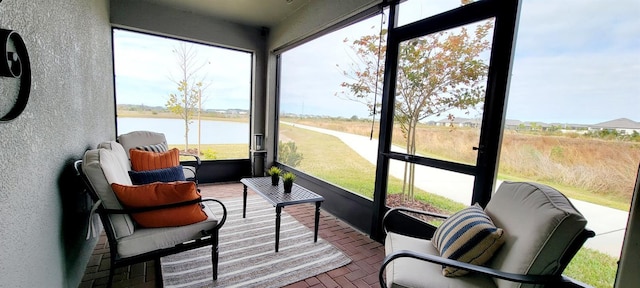 sunroom featuring a water view