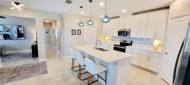 kitchen featuring pendant lighting, sink, white cabinetry, an island with sink, and stainless steel appliances