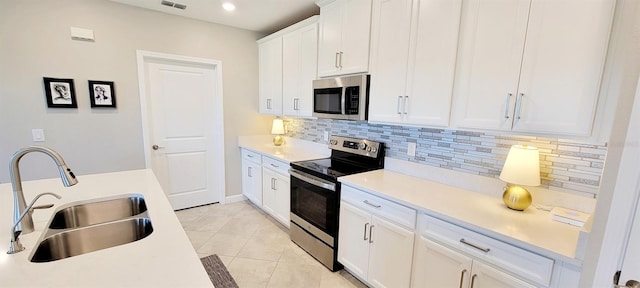 kitchen featuring white cabinets, appliances with stainless steel finishes, tasteful backsplash, sink, and light tile patterned floors