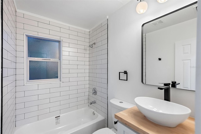 full bathroom featuring toilet, vanity, and tiled shower / bath combo