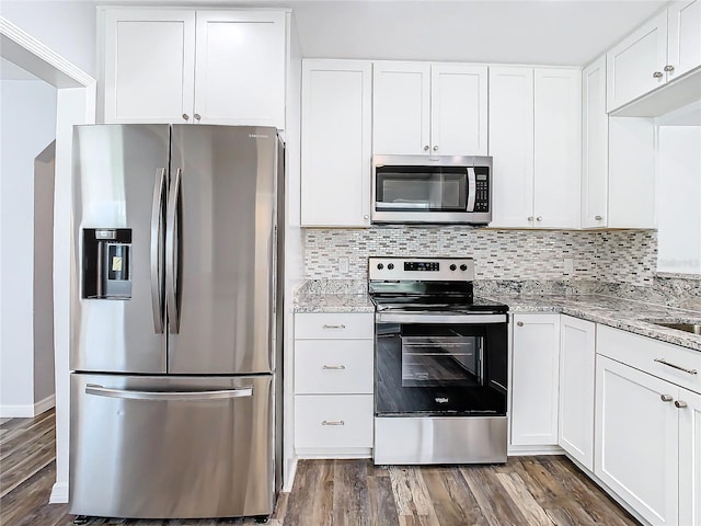 kitchen with dark hardwood / wood-style flooring, appliances with stainless steel finishes, decorative backsplash, and white cabinets