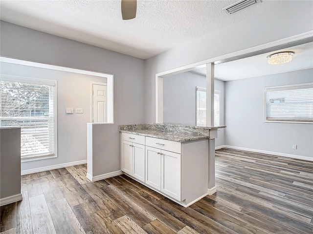 kitchen featuring white cabinetry, a textured ceiling, dark hardwood / wood-style floors, and light stone countertops