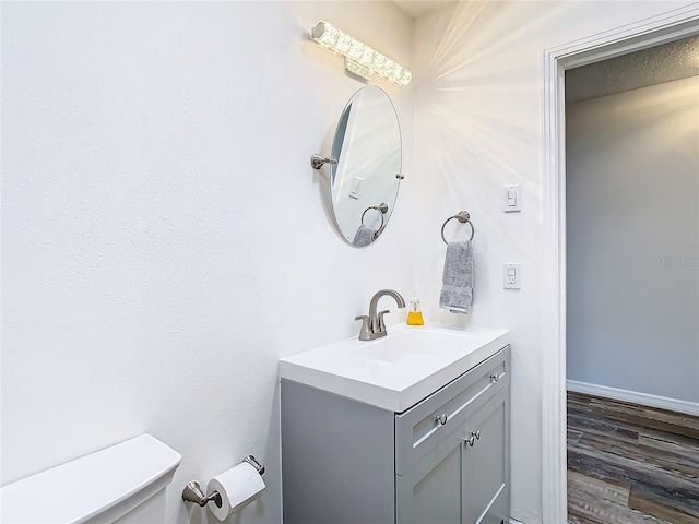 bathroom with toilet, vanity, and hardwood / wood-style flooring