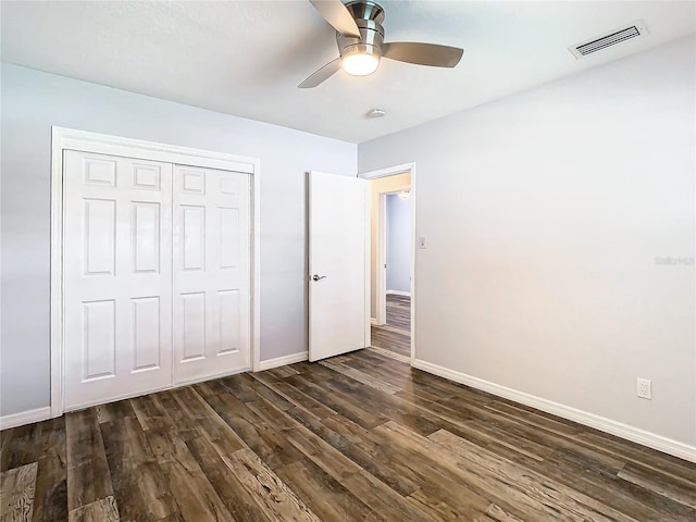 unfurnished bedroom with dark wood-type flooring, ceiling fan, and a closet