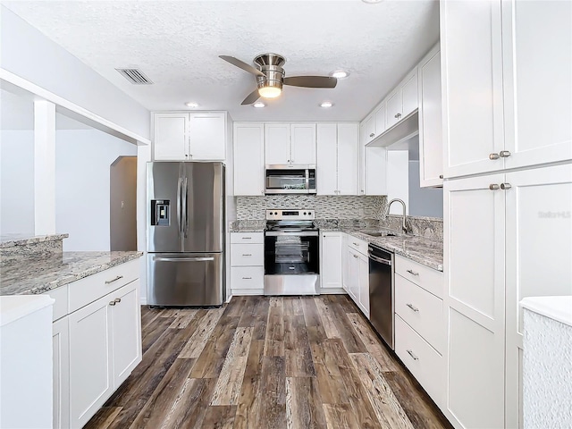 kitchen with stainless steel appliances, white cabinets, and dark hardwood / wood-style flooring