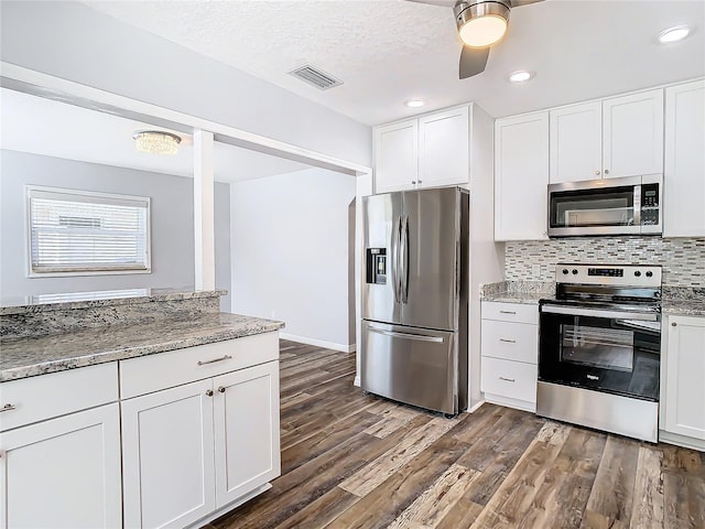 kitchen with dark wood-type flooring, light stone countertops, white cabinets, and stainless steel appliances