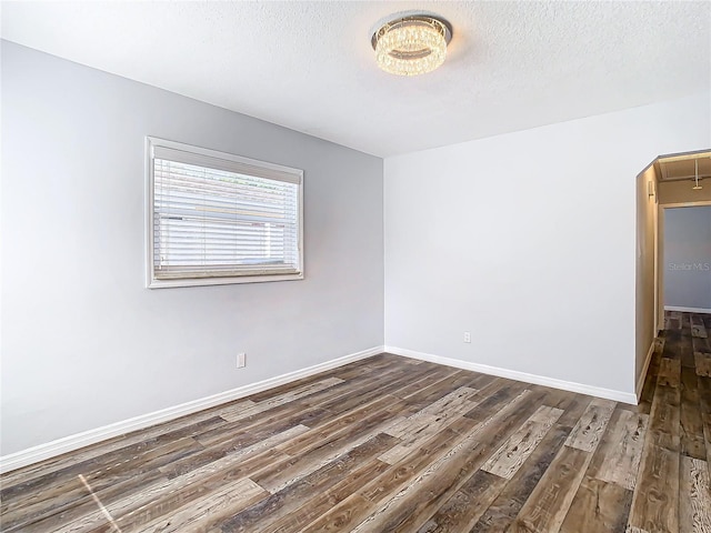 spare room with dark wood-type flooring and a textured ceiling