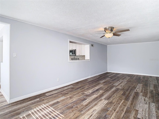 empty room with ceiling fan, a textured ceiling, and dark hardwood / wood-style flooring