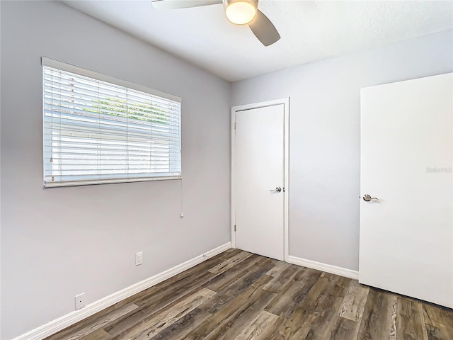 unfurnished bedroom featuring dark hardwood / wood-style flooring, ceiling fan, and a closet