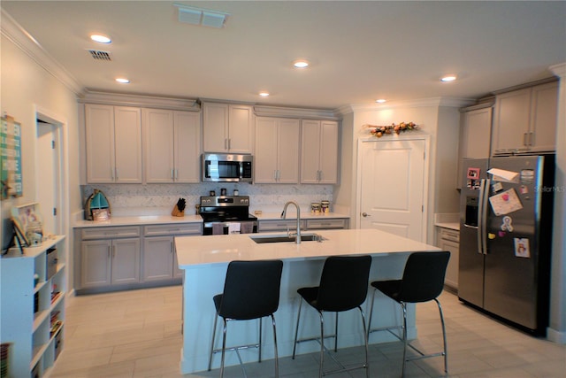 kitchen featuring appliances with stainless steel finishes, sink, a kitchen bar, and a center island with sink