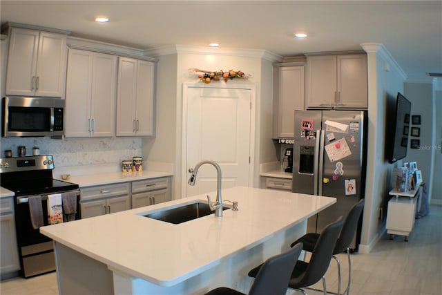 kitchen with a center island with sink, appliances with stainless steel finishes, sink, and crown molding