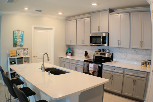 kitchen with sink, a kitchen bar, a center island with sink, and stainless steel appliances