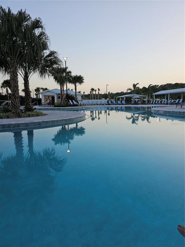 pool at dusk featuring a water view