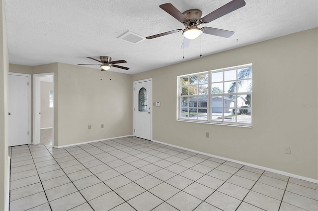 spare room featuring a textured ceiling, ceiling fan, and light tile patterned floors