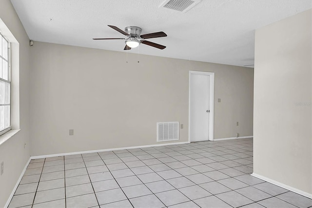 tiled empty room featuring a wealth of natural light, a textured ceiling, and ceiling fan