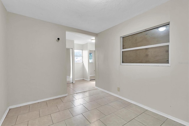 unfurnished room featuring a textured ceiling and light tile patterned floors