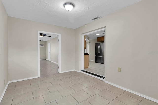 tiled empty room featuring a textured ceiling and ceiling fan